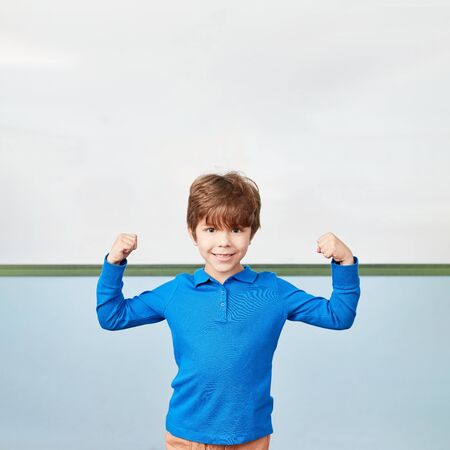 Boy as a student smiles proudly and clenches his fists as a winner in elementary school
