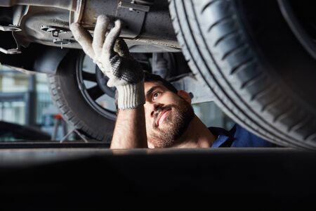 Mechatronics engineer or mechanic in the repair of car exhaust for main inspectionの写真素材