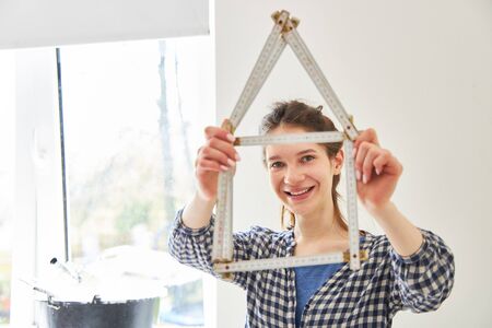 Young woman with folding rule house as a symbol of home construction and home renovation
