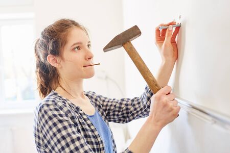 Young home improvement woman with hammer on a wall while renovating her apartmentの写真素材