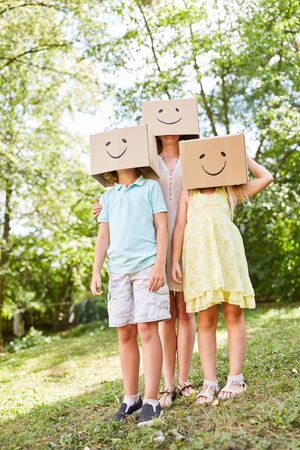 Mother and children play with funny painted cardboard boxes on their headsの写真素材