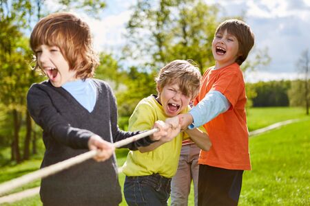 Children's team has fun in tug-of-war competition on a children's birthday party in the parkの写真素材