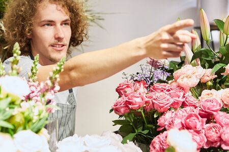 Young florist as a seller with assortment of flowers in the flower shopの写真素材