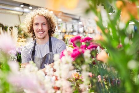 Smiling florist between colorful cut flowers in his flower shopの写真素材