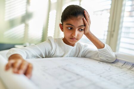 African child as an architect looks thoughtfully at a drawing