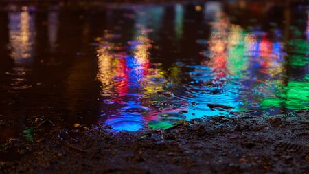 Reflection of colorful lights in the evening in puddle as an abstract backgroundの写真素材