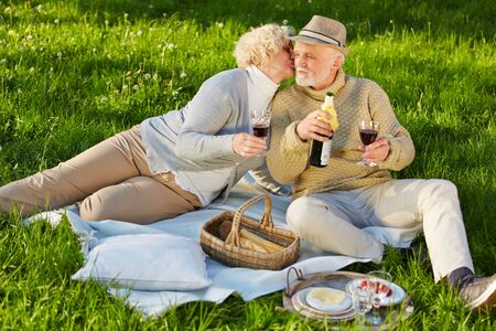 Two seniors kissing at a picnic in the summer in a meadowの写真素材