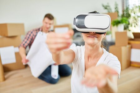 Young woman uses virtual reality glasses in the new apartment for space planning
