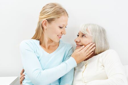 Granddaughter lovingly caresses the cheek of her old grandmotherの写真素材