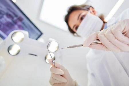 Dentist holds hand instruments for examination or treatment in the medical office or clinicの写真素材