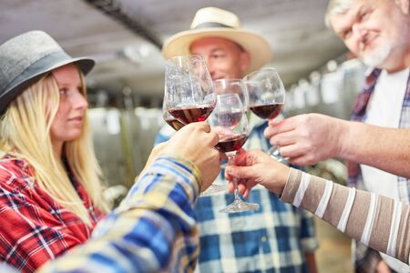 Group of winegrowers toasting with red wine together in the wineryの写真素材