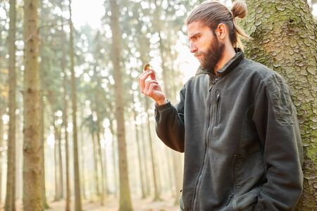 Young ranger in the woods critically looks at a mushroom for the classification