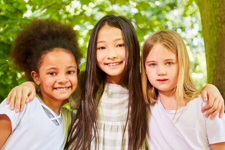 Three multicultural girls as girlfriends in kindergartenの写真素材