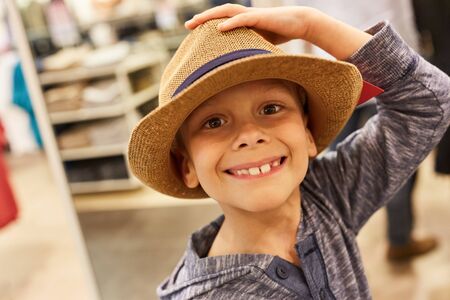 Happy boy in hat buying in a fashion store in the shopping centerの写真素材