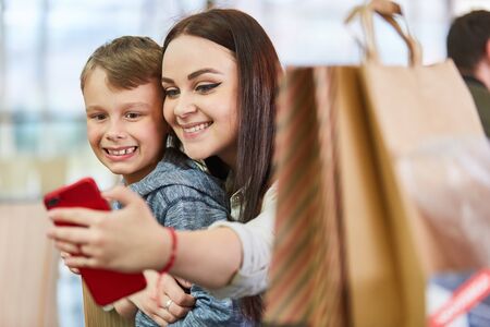 Brother and sister take a selfie with their smartphone while shoppingの写真素材