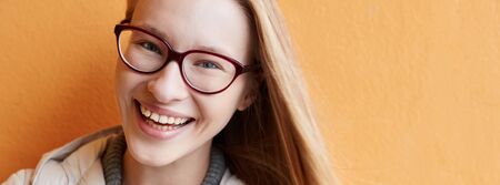 Panorama of a blonde young woman against an orange wall