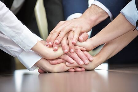 Business team stacks many hands for motivation on a table