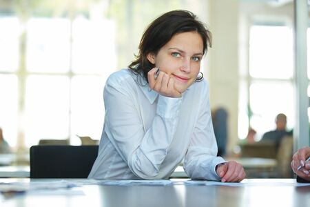 Young businesswoman sitting thoughtfully at the table in the office