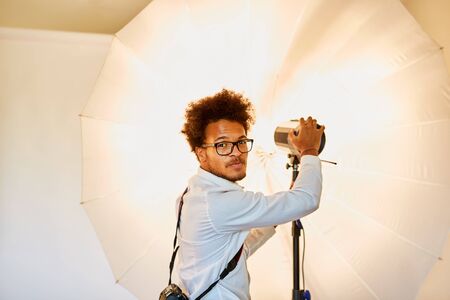 Young photographer with studio light and flashlight at the studio illuminationの写真素材