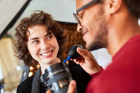 Photographer with lens cleaning with bellows in the photo studio next to assistantの写真素材