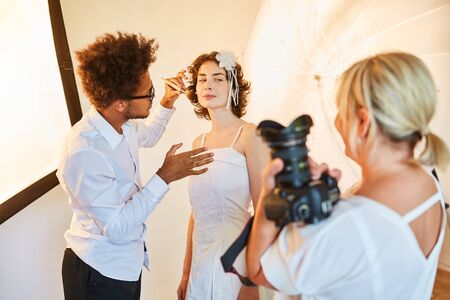 Make-up artist styling the bride for the photo shoot on the wedding dayの写真素材
