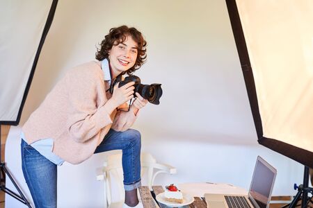 Smiling food photographer with camera and piece of pie in the photo studioの写真素材