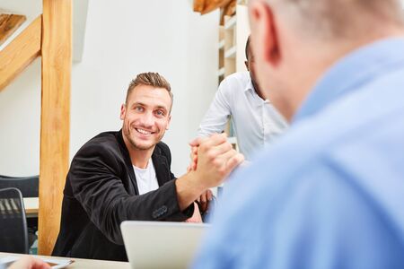 Young man as a student or entrepreneur in the library with friends and colleaguesの写真素材