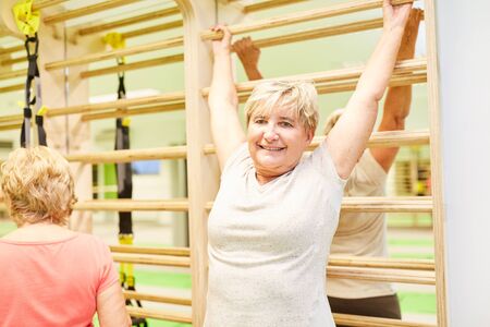 Senior doing back exercises on the wall in physiotherapy in the gymの写真素材