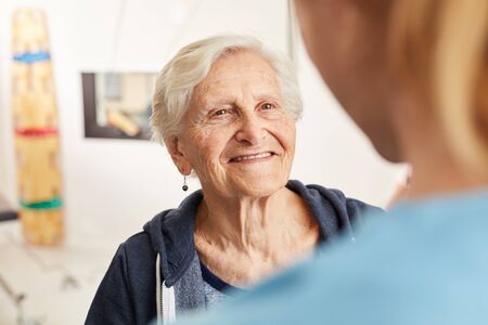 Satisfied senior woman in rehab together with physical therapist