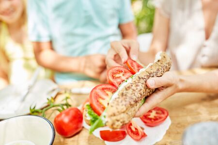 Family having healthy breakfast with tomatoes on fresh baguetteの写真素材