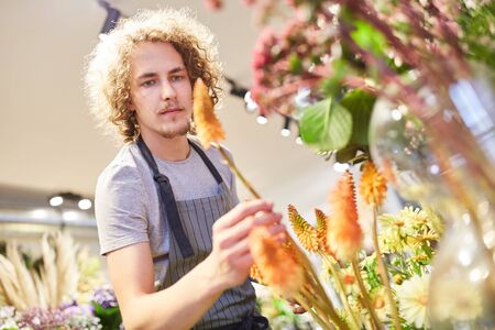 Florist or trainee controls cut flowers in his flower shopの写真素材