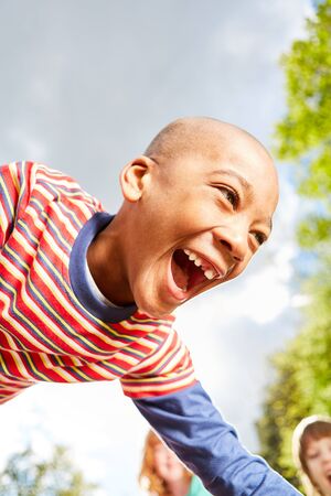 African boy plays with enthusiasm with his friends in summer