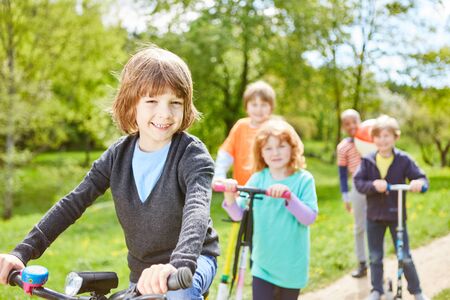 Children in the international kindergarten make a trip by scooter and bicycle