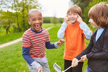 Three laughing kids as friends have fun together and make faces