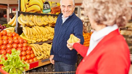 Senior couple together while shopping for fruits and vegetables in supermarketの写真素材