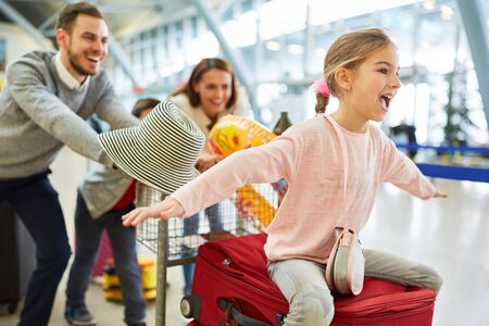 Laughing girl and family in the airport terminal are looking forward to the vacation tripの写真素材