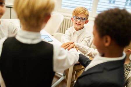 Children as a business team while stacking hands for motivation and team buildingの写真素材