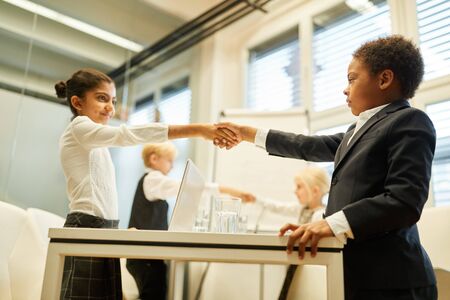 Business kids sign a contract with a cooperation with handshake in the officeの写真素材