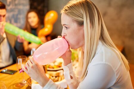 Young woman and friends together while inflating balloons at a partyの写真素材