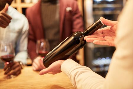 Wine waiter presents a bottle of red wine during a tasting or wine tastingの写真素材