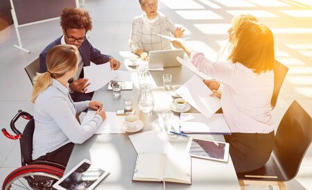 Inclusion among business people Meeting in the office with a woman in a wheelchair at the table during project planningの写真素材