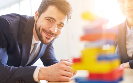 Team building in the business workshop with people around a tower made of building blocks