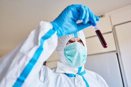 Laboratory employee in protective clothing with Covid-19 blood sample for test in the laboratory