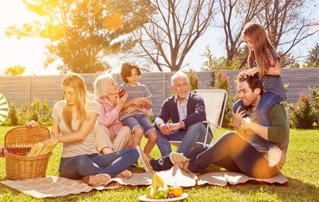 Family with children and grandparents celebrates birthday in the garden with picnicの写真素材