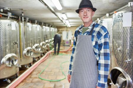 Wine master or master brewer in the winery or brewery with fermentation tanks