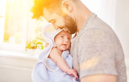 Father smiling while drying baby with a towel after bathingの写真素材