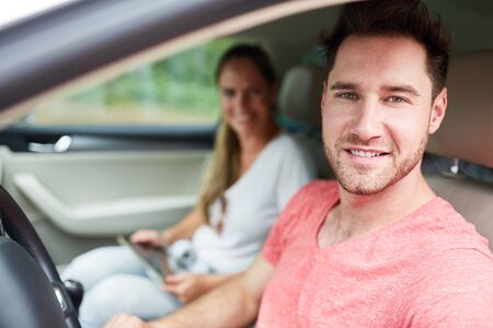 Young man as a satisfied motorist on the journey in the car or rental carの写真素材