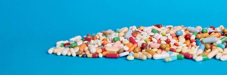 Many colorful medicines drugs lie on a blue background with copy space