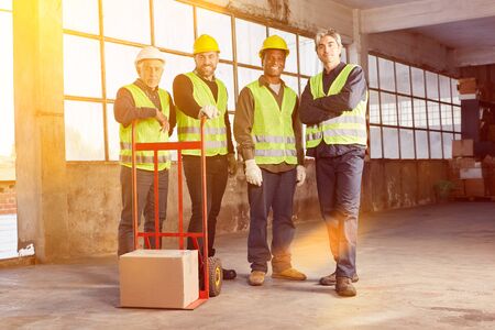 Industry workers group in hall of a factory with package on hand truck