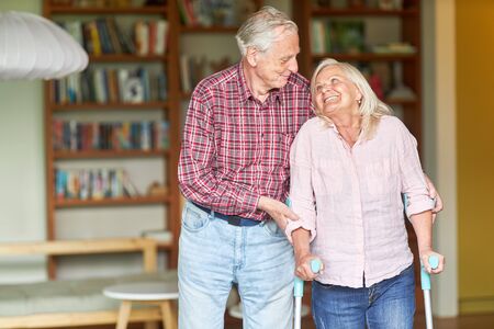 Senior caring to support his wife while walking on crutches